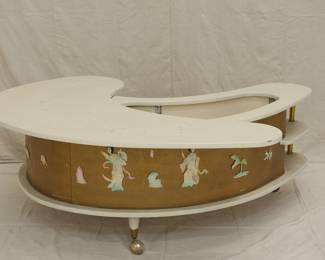 Another view of the "Grand Server" mid-century modern boomerang/kidney shaped coffee table with collapsible bar cabinet, manufactured by A.H. Stock Manufacturing Company. This design was showcased at the 1964 World’s Fair in New York City as an example of American modern furniture. With two external shelves, locking side cabinet doors and resting on legs with casters, this table’s white laminate top swings open to reveal an inside compartment with a mechanical tray: just pull up on the brass handles which lock the tray into place at table height. Wrapped with textured gold vinyl on the sides, with applied mother of pearl pieces in Asian decorative motif.