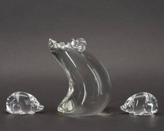 Add to your art glass menagerie with these three crystal clear glass hand formed pig figurines from a series of Special Animals that Steuben introduced in the 1970s, designed by Lloyd Atkins. Each piece signed "Steuben." Sitting pig with its eloquently ruffled ears is 4-1/4 inches L x 3-1/2 inches W x 6 inches H, and the small pair of pigs are 2-3/4 inches L x 1 inches W x 1-1/2 inches H.