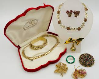 This S & G Fifth Avenue parure in its original velvet red case is from the 1950's-1960's, with a necklace and bracelet in gold tone block design with lovely chaton cut clear rhinestones attached to the square cut blocks. Also shown are some of the lovely brooches available, a gold ribbon shaped brooch with pendant scent ball / pomander, and a gold tone leaf shaped link necklace with floral form clusters of warm gold and red rhinestones, and a pair of vintage floral spray form clip earrings with deep red rhinestones