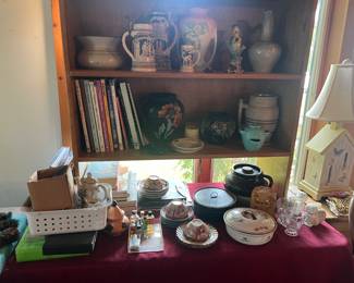 Below the wooden shelf, the table displays china and pottery items. Take a look at the lamp on the right! 