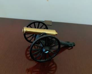 Golden cannon with cast iron wheels. Shelf decor.