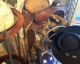 Saddle and stand, American presentation flag and cowboy hat.