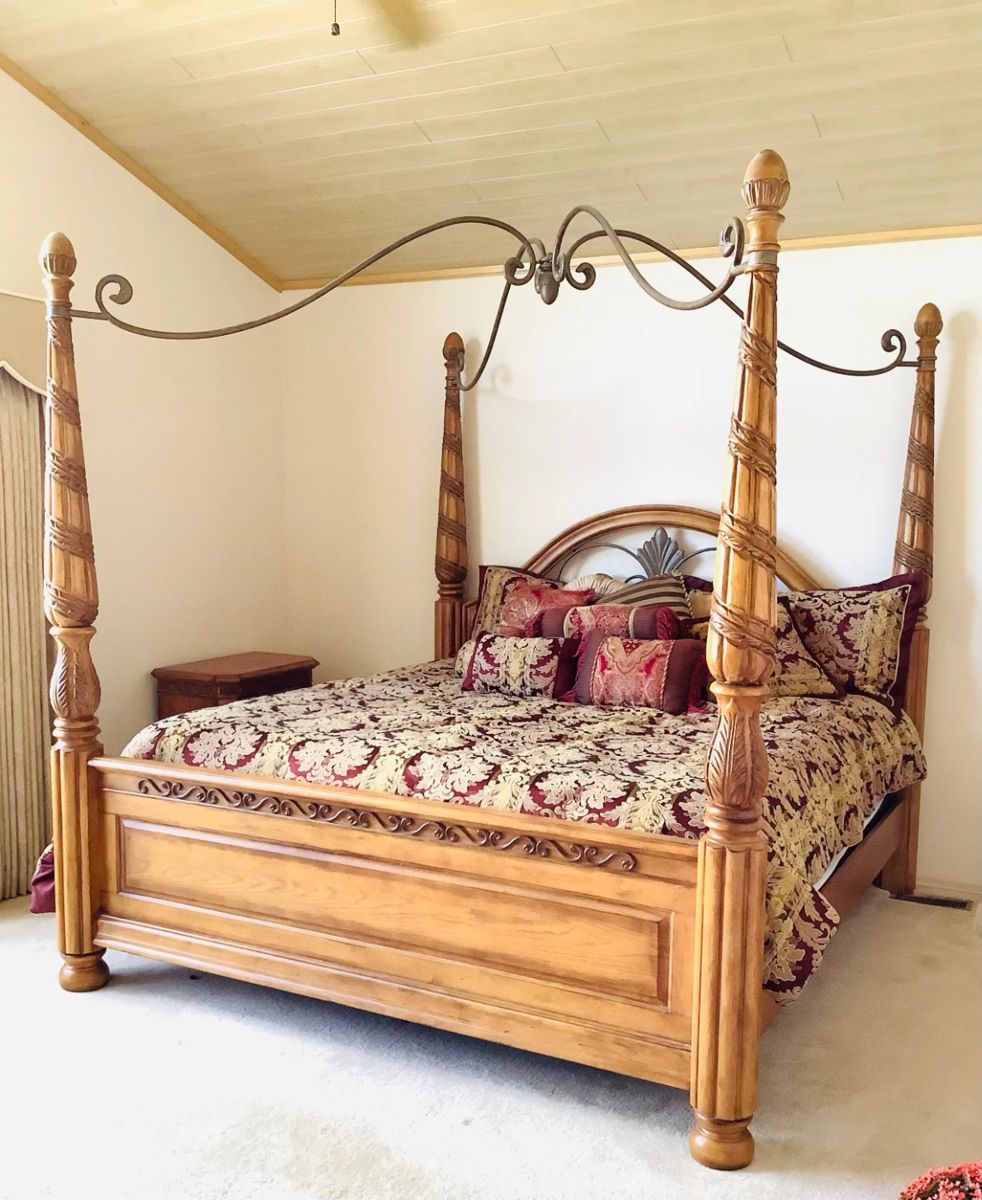 Ashley four poster king size wood bed featuring an intricate carved design and metal canopy. Assembled H 82" x W 82" x D 85". Center of canopy measures approximately 6" higher than the four posters. Matches lots 3 and 9. NEW King sized Copper Infused mattress and boxspring. (See paperwork) Bedding optional. Objects shown in background are not included. Bring tools to disassemble bed. Receipt from consignor shows Ashley as the brand of furniture.