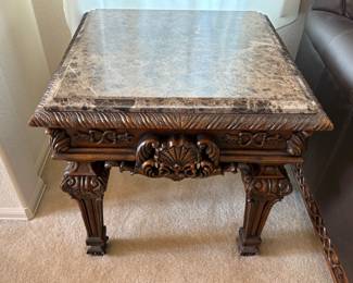 Appears to be a marble topped end table which features an intricately carved base. Made in China. H 27" x W 28" x D 28". Minor nicks and scratches. Matches lot 92. Receipt from consignor shows Ashley as the brand of furniture.