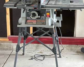 Craftsman 10" table saw. Model 315.218050. Folds for easy storage. Powers on. Objects shown in background are not included.