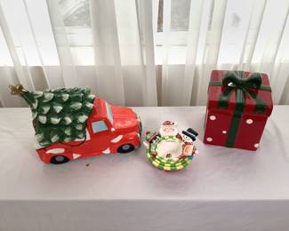 Two( 2) cookie Jars- one by David's Cookies featuring a red truck and christmas tree, H 9" x W 5 1/2" x D 11", One in the shape of a gift wrapped box, H 8 1/2" x W 6" x D 6". Also includes one (1) set of Temptations Presentable Ovenware by Tara measuring cups Appear new in box.