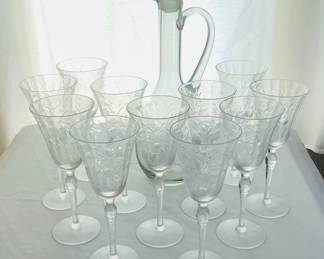 Eleven (11) etched glass wine glasses, H 8 1/2" x 3 1/2" diameter. No markings. One has a chip along the rim. Etched glass decanter with stopper and handle. Made in Peru. H 16" x 5" diameter.