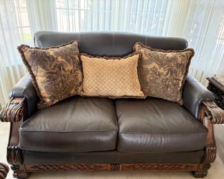 Lane faux leather loveseat featuring a classical, wood carved frame. Excellent condition. H 38" x W 66" x D 42". Matches lots 93 and 96. Receipt from consignor shows Lane as the brand of furniture.
