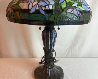 Bronze style lamp featuring "stained glass" style plastic shade in blues, greens, and purples. H 25"H x 17.5" diameter. No manufacturer found. Powers on.