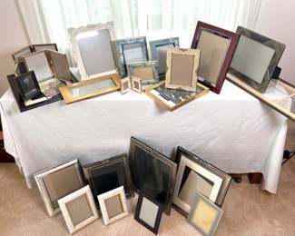 Twenty (20) +/- photo frames ranging in size from H 2" x W 3" to H 10" x W 27". See photos for sampling.