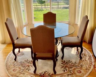 Green River Wood dining set. Includes (4) upholstered chairs with carved wood legs. H 43" x W 17" x D 19". Round glass topped table with a metal and wood base. H 30" x 53" diameter. Rug not included.