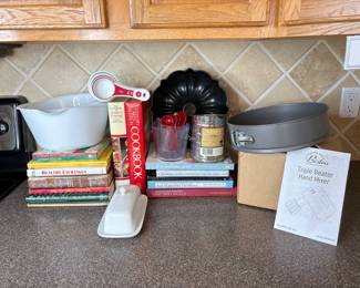 New in box Wolfgang Puck hand mixer. Nonstick cheesecake and bundt pans. Mixing bowls, measuring spoons, cups and more. A selection of cookbooks. See photos for details.