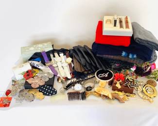 An assortment of women's accessories including several pairs of leather gloves, scarves, a hand carved soapstone jewelry box H 3" x W 7" x D 3", women's belts, brooches and more. See photos for sampling.