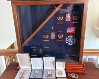 Approx. (20) medals for fire service & Air Force Service, epaulets with insignia associated with rank of fire chief. Wood case with glass door, H 28" x W 22 1/4" x D 5 1/4. See photos for sampling.