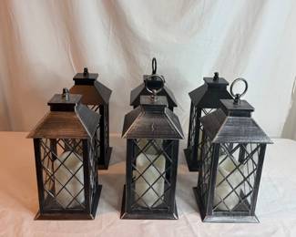 Six (6) lanterns with battery powered candles inside. Made of metal. Untested. H 12" x 5" square. Several are missing the hooks on the top of the lantern.