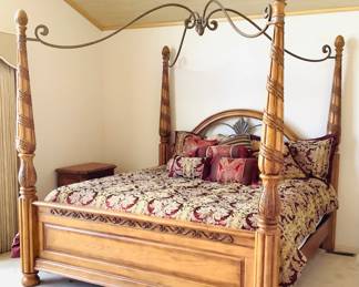 Ashley four poster king size wood bed featuring an intricate carved design and metal canopy. Assembled H 82" x W 82" x D 85". Center of canopy measures approximately 6" higher than the four posters. Matches lots 3 and 9. NEW King sized Copper Infused mattress and boxspring. (See paperwork) Bedding optional. Objects shown in background are not included. Bring tools to disassemble bed. Receipt from consignor shows Ashley as the brand of furniture.
