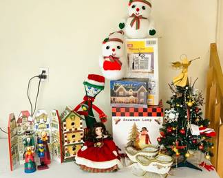 An assortment of Christmas decor which includes an animated singing streetlamp H 18", a gingerbread house style bird house H 13 1/2" x 7" square (appears to be have been dropped and edges have separated), a new in box 18" lit pinecone tree, a new in box snowman light and more. See photos for sampling.