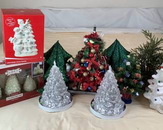 An assortment of Christmas trees including a battery operated ceramic tree with lights (a few bulbs missing) H 15" x 8" diameter, a new set of Loft Living flameless Christmas trees, (2) LED Christmas trees, and more. See photos for sampling.