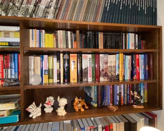 Wall shelves packed with a variety of of books … and a few Vtg squeaky toys 