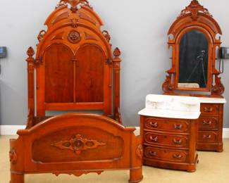 A 19th century Victorian Renaissance Revival Period three piece bedroom set. Walnut construction with applied Burl panels and carved detail with White molded marble tops. Includes a high back bed (64 x 82 x 103" high) with an arched headboard with carved cartouche over two arched panels, curved footboard with shaped panel and carved medallion. Matching dresser (64 x 82 x 96 1/2" high) with swing mirror and candlestands over a Marble top and three lower drawers with carved foliate pulls. Matching commode (31 1/2 x 20 1/2 x 37" high) with a Marble top and shaped backsplash with two candlestands over a three drawer base with carved foliate pulls. Older refinishing with minor wear, some older repair, replaced backsplash on commode. ESTIMATE $1,000-2,000