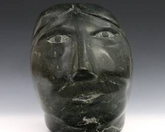 A 20th century Inuit carved Serpentine sculpture of a female head from the Cape Dorset (Kinngait) hamlet, Qikiqtaaluk Region, Canada. Retains original "Canadian Eskimo Art" Igloo tag citing artist as "Pookalook" (n.d.), also includes original 1970's purchase receipt from "Eskimo Art Inc." in Ann Arbor, MI. Minor surface wear, natural veining across top and back of head. Approx. 7 x 10 x 10" high overall. ESTIMATE $400-600