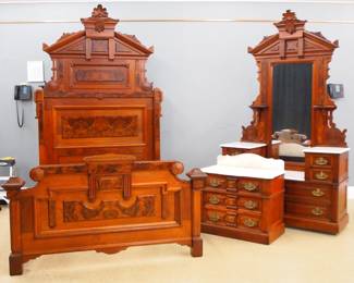 A 19th century Victorian Renaissance Revival Period three piece bedroom set. Walnut construction with applied Burl panels and carved detail with White molded white marble tops. Includes a high back bed (64 1/2 x 83 x 103" high) with a pediment headboard with shaped sides and Burl panels, shaped footboard. Matching drop center dressing case (55 x 21 x 97" high) with swing mirrored back and candlestands over a tree piece Marble top with two short drawers on each side and two long lower drawer. Matching commode (33 1/2 x 19 x 33" high) with a Marble top and shaped backsplash with over a three drawer base with fancy cast pulls. Older refinishing with minor wear, some older repair, lacks 3 of 4 side rail brackets, married marble on commode fits poorly, replaced pulls. ESTIMATE $600-800