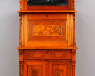 A 19th century Victorian Eastlake Period ladies desk. Walnut construction with Burl panels, turned columns and carved decoration features a mirrored backsplash with shaped crest over a fold-down writing desk with mirrored front panel and inset felt writing surface which opens to reveal a fitted interior with compartments and drawers, above two paneled doors and a simple bracket base. Older refinishing with minor wear, replaced felt. 32 x 18 x 67 1/2" high overall. ESTIMATE $200-300