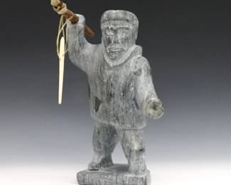 Jacob Thomassiah, Inuit (Port Burwell), 1917-1984. A 20th century carved Soapstone figure of a hunter holding a wooden spear with polished bone implements and sinew line. Signed with "E8-167" disc number at underside, retains original "Canadian Eskimo Art" Igloo tag. Minor surface wear, bone blade repaired. 9" high. ESTIMATE $300-400