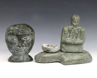 Two 20th century Inuit carved stone sculptures. Includes an assemblage on a shaped base depicting a woman and with bowl and bone spoon from the Nanook Group, Clyde River, and a carved bust of a man by Jobie Inukpuk (Inuit, Port Harrison/Inukjuak, 1934-1983). Assemblage signed in syllabics at underside and retains original "Canadian Eskimo Art" Igloo tag citing artist as "Pauloosie" (n.d.), bust signed with "E9-880" disc number at underside and retains a paper label citing artist as "Jobie" with original 1970's purchase receipt from "Eskimo Art Inc." in Ann Arbor, MI. Bowl from assemblage repaired with broken dowel attachment, minor surface wear. Up to 7 1/2 x 6 1/4" high overall. ESTIMATE $300-500
