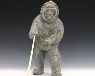 A 20th century Inuit carved stone figure of a hunter with polished bone spear. Minor wear. 12" high. ESTIMATE $300-500
