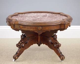 A 19th century Victorian Eastlake Period coffee table (converted from a taller parlor table). Walnut construction with a shaped top and inset Marble on a base with shaped legs and porcelain castors. Older finish with some wear, height reduced approx. 10". 30 x 25 x 19" high overall. ESTIMATE $100-150