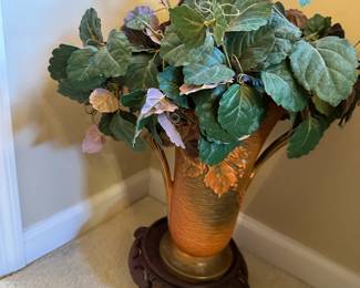 Artificial plant in a decorative pitcher on a stand
