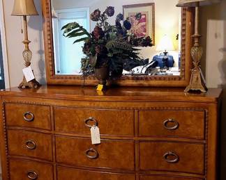 Primary bedroom triple dresser with mirror, lamps & floral arrangement