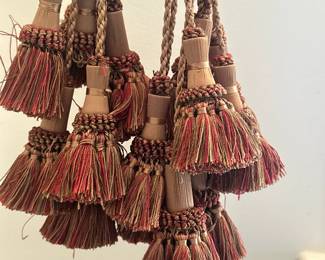 (8pc) Collection of Decorative Tassels | Collection of decorative tassels with braided cords, cylindrical centers wrapped in intricate weaves, and fringed ends in warm multicolored threads of deep red, brown, and gold, likely used for curtain tiebacks or accents. - l. 24 in