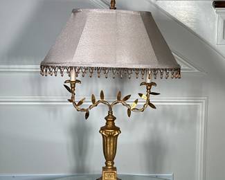 Gilded Brass Candelabra Table Lamp | Antique (early 20th-century) Louis XIV style gilded brass candelabra table lamp with two foliate/leafy arms, a vase-shaped center column on a black marble base, and an oblong metallic shade adorned with crystal teardrop fringe. -h. 20 x w. 19 in