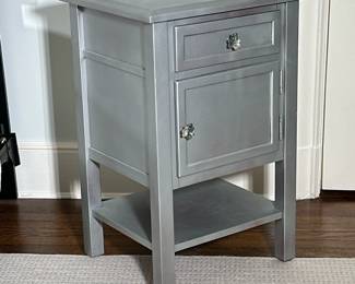 Two-Drawer Painted Side Table - Grey | Wooden side table painted grey with flat top, one drawer and one cabinet door with jeweled floral knobs, an open bottom shelf, and a metallic finish that adds modernity. - h. 29 x w. 18.5 x d. 17 in