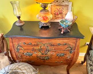 Vintage Hand-Painted Bombe Chest with Floral Details, Antique Hurricane Lamp, Glassware, and Decorative Accents