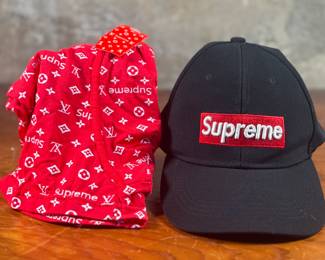This lot features a hat and briefs by Supreme. The briefs are brand new with tags. Supreme is an American clothing brand established in Manhattan, New York in April 1994. The company focuses on streetwear, skateboarding, and hip hop fashion trends. In December 2020, the U.S.-based apparel and footwear company VF Corporation bought Supreme for $2.1 billion.