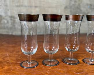 This lot features a set of four Dorothy Thorpe silver band glasses in good overall condition. Thorpe was a mid-century designer, not a manufacturer, of glassware. She purchased “”blanks”” from manufacturers then decorated them with her personal designs. Inspired by trips to Hawaii, Thorpe originally designed glassware with eucalyptus, irises, roses and narcissus flowers.