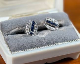 This lot features a pair of vintage 14k rhodium plate earrings. Each earrings has a center channel of five square step cut synthetic sapphires and bead set to each side of the center channel are five round diamonds into a bowed vertical bar. Total approx. weight of 3.00 grams. This set of earrings come with paperwork from Pacific Gem Laboratories and a box to store them in.
