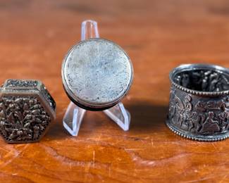This lot features a collection of sterling silver items including a small box made of Gutta-percha with a sterling silver lid depicting a hunting scene. Total approx. weight for all three items is 86.39 grams. Gutta-percha is a natural, thermoplastic material derived from the sap of the Palaquium tree, commonly used in dentistry as a filling material for root canals. It’s known for its biocompatibility and ability to be softened with heat and molded, making it suitable for sealing the root canal system after a root canal procedure.