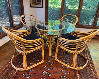 Oval Glass Top Dining Table with Rattan Base (48” x 26”) with four chairs. Table and chairs will be sold separately.