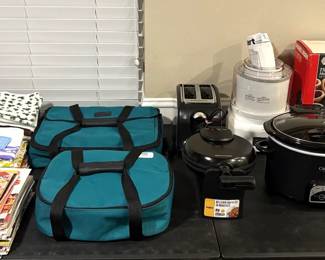 SOME KITCHEN TOWELS, RECIPE MAGAZINES, PYREX DISHES IN INSULATED CARRIERS, AND SMALL KITCHEN APPLIANCES.