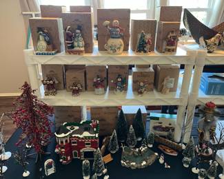 Christmas village collectibles and holiday decorations, including figurines, miniature houses, and bottle brush trees.