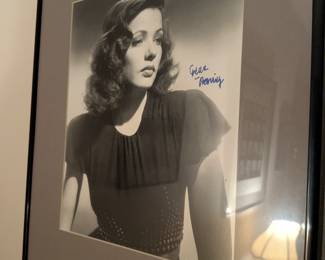 Framed black-and-white photo with a signature that appears to be from Gene Tierney, a stunning actress known for her roles in film noir and dramas.