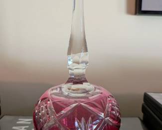This is a beautiful decorative glass bell, likely from the mid-20th century. The bell features a stunning ruby red color with an elegant cut-glass pattern on its base and a clear glass handle. It's a charming and classic piece of decorative glassware, perfect for a display cabinet or as an accent on a mantelpiece.