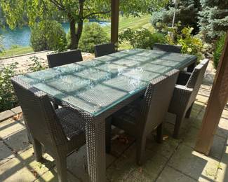 Large outdoor woven design set with glass top table and 6 matching chairs.