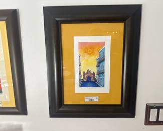 Framed print with yellow mat, featuring a colorful colonial street scene.