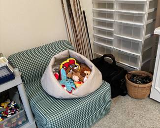 Dog bed and toys is sitting on green check foam chair which becomes a bed when More storage containers and interesting spears
