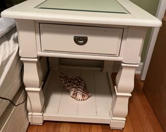 matching white bedside table with shutter detail top under beveled glass